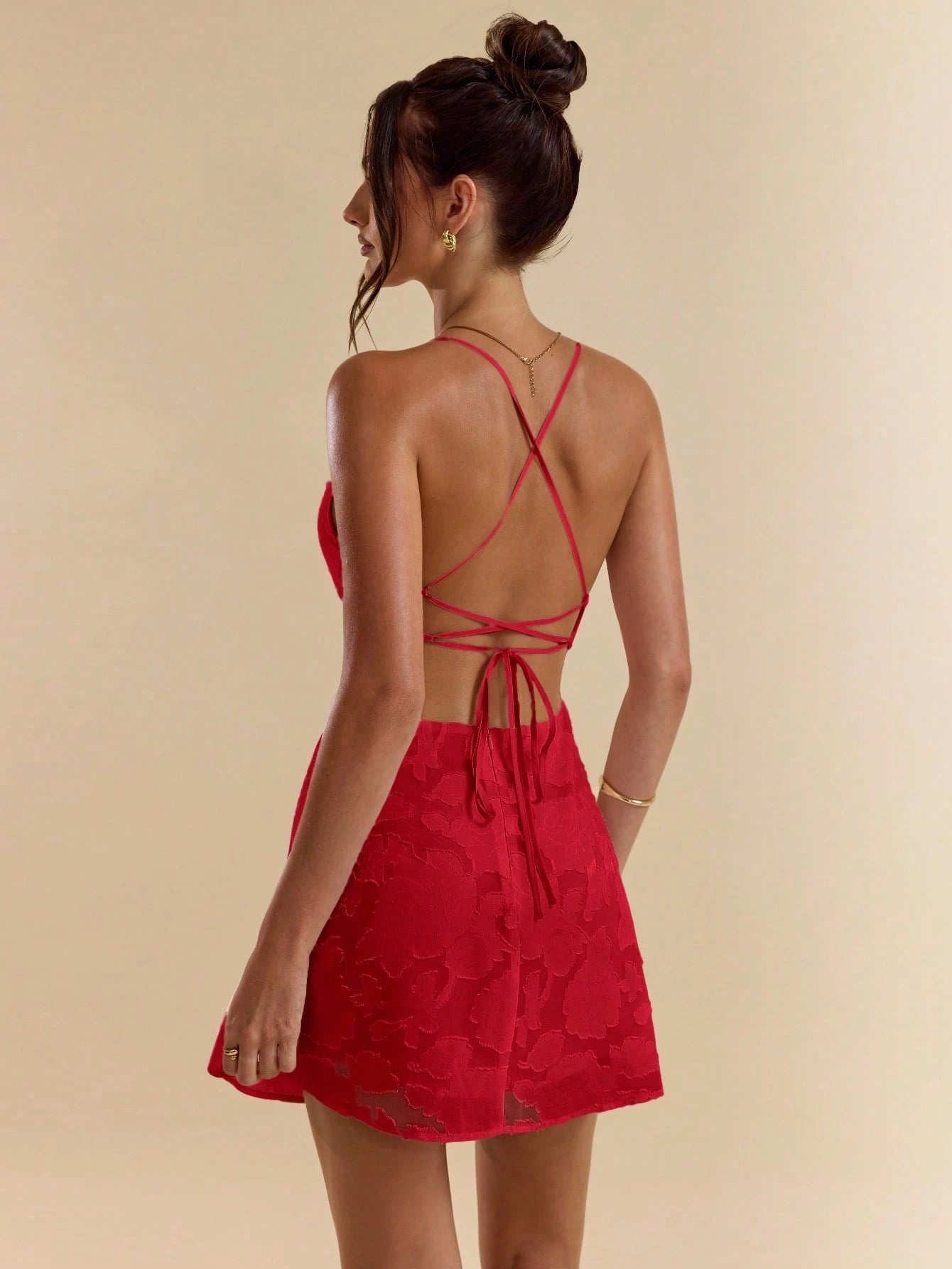 Chic solid pink bodycon mini dress with low back, tie straps, and textured A-line silhouette.