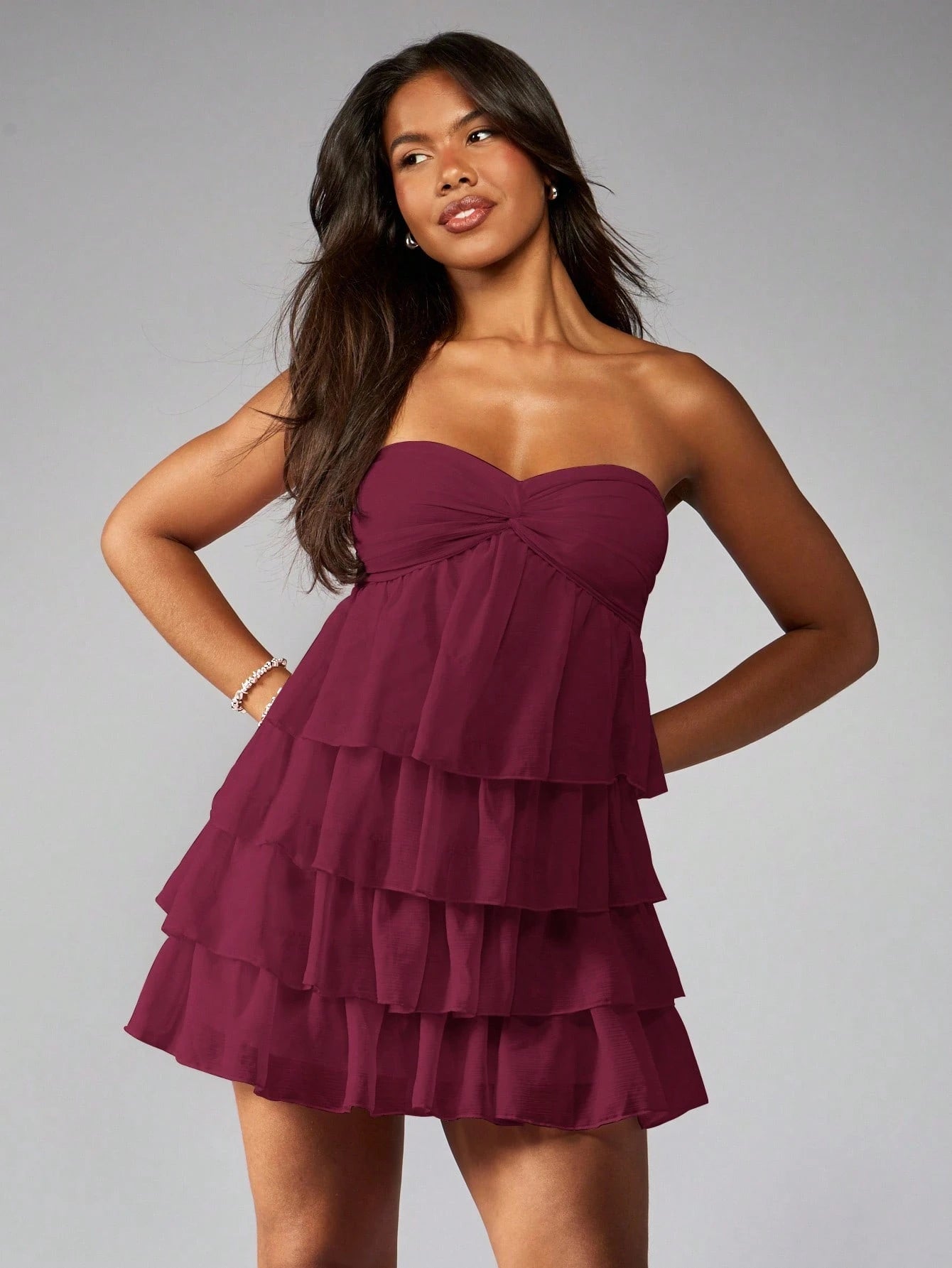 Elegant strapless mini dress with tiered ruffles, twist-front detail, and empire waist.